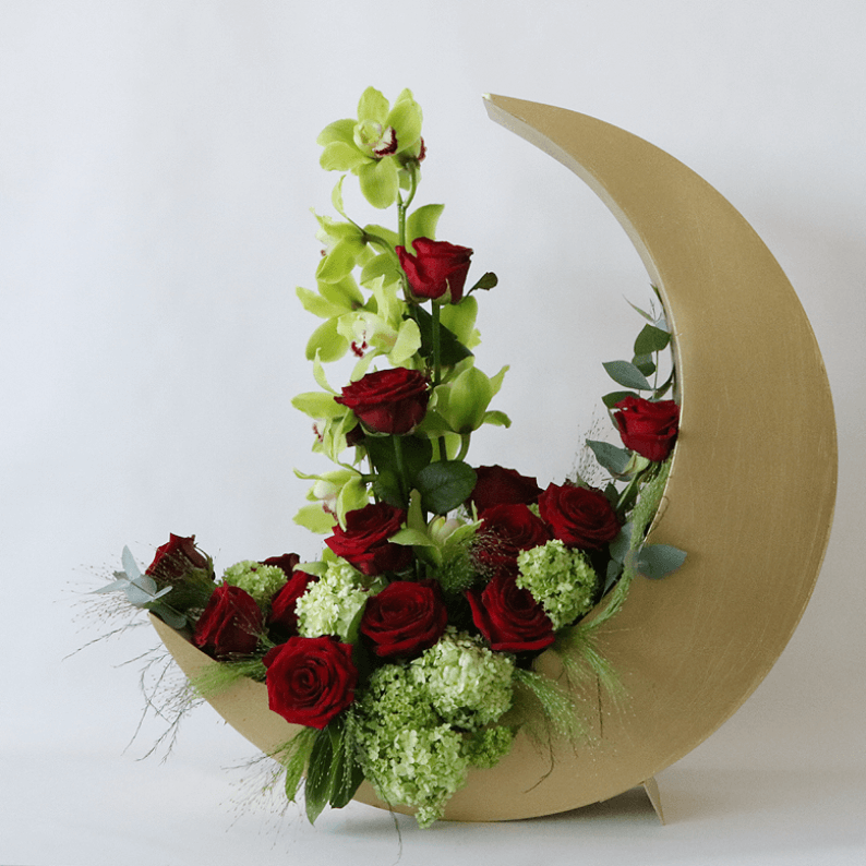 red and green flowers in a crescent moon red rose and cymbidium in a gold crescent moon