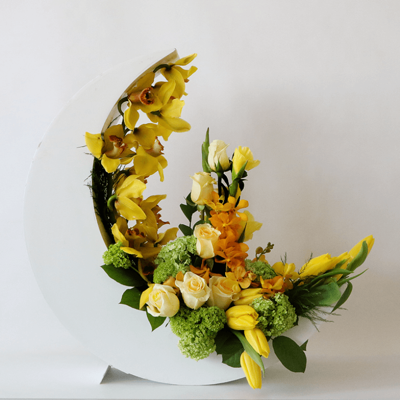 Crescent moon design with yellow flowers Yellow tulips, cymbidiums, orchids arranged in a white crescent moon