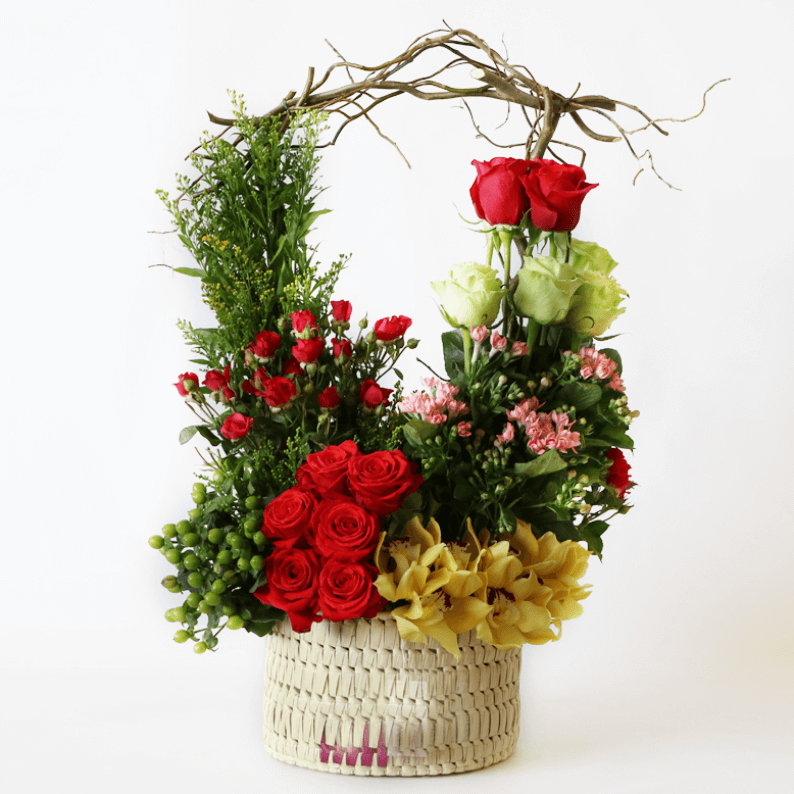 Red, green and yellow arrangement Red and green roses with spray roses, yellow cymbidium orchids in a basket