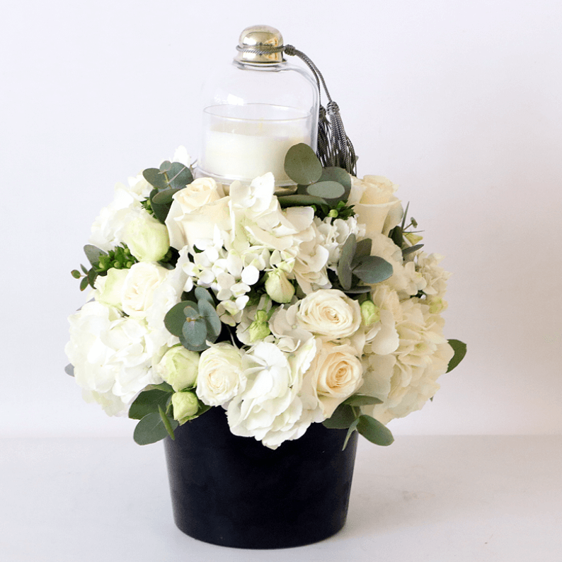 Flowers and Candles Scented candle with white and green flowers arranged including roses and hydrangea,